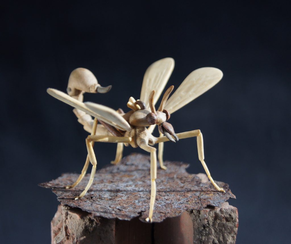 A wooden sculpture of a frightening insect with a sting
