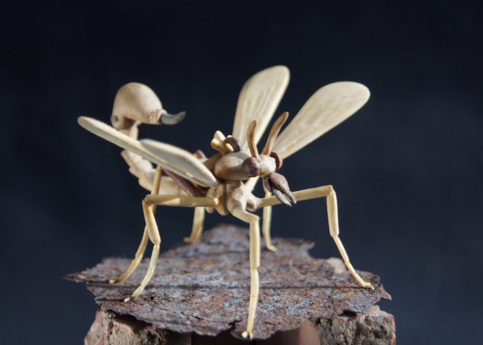 A wooden sculpture of a frightening insect with a sting