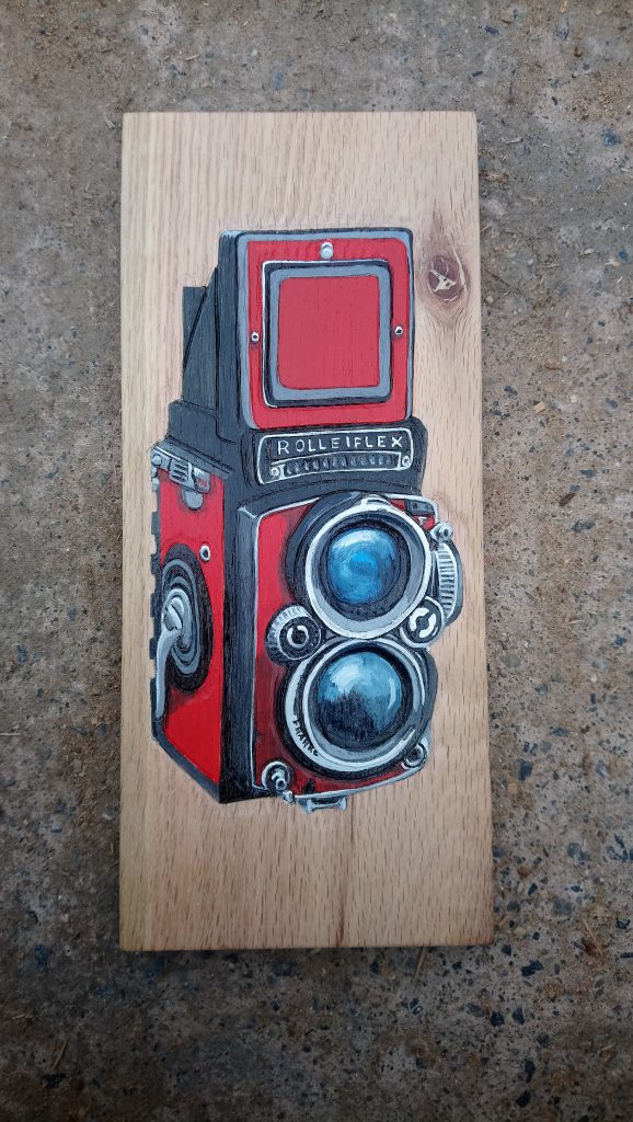 painted carved relief of a camera