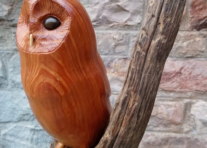 woodcarving of a carved wooden owl perched on a branch