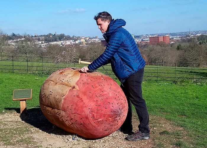 artist Luke Jerram hammers a coin into his sculpture New Beginnings at Ashton Court in Bristol