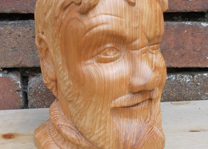 woodcarving of a bearded man's head, winking