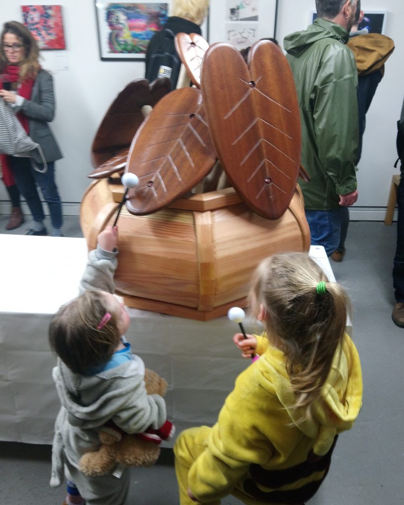 Young children playing wooden percussion sculpture